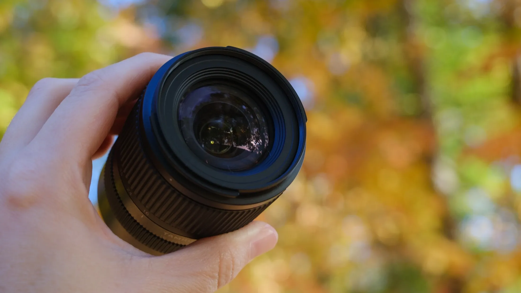 Tamron 16–50mm F2.8 A в руке фотографа, вид со стороны передней линзы