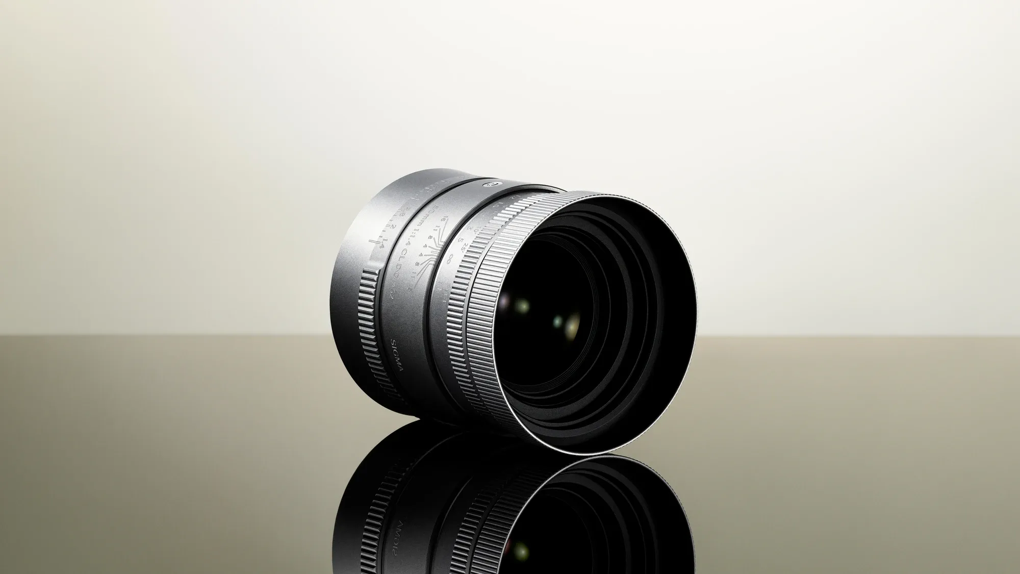 Серебристый Sigma 50mm F1.4 CL DG на отражающей поверхности