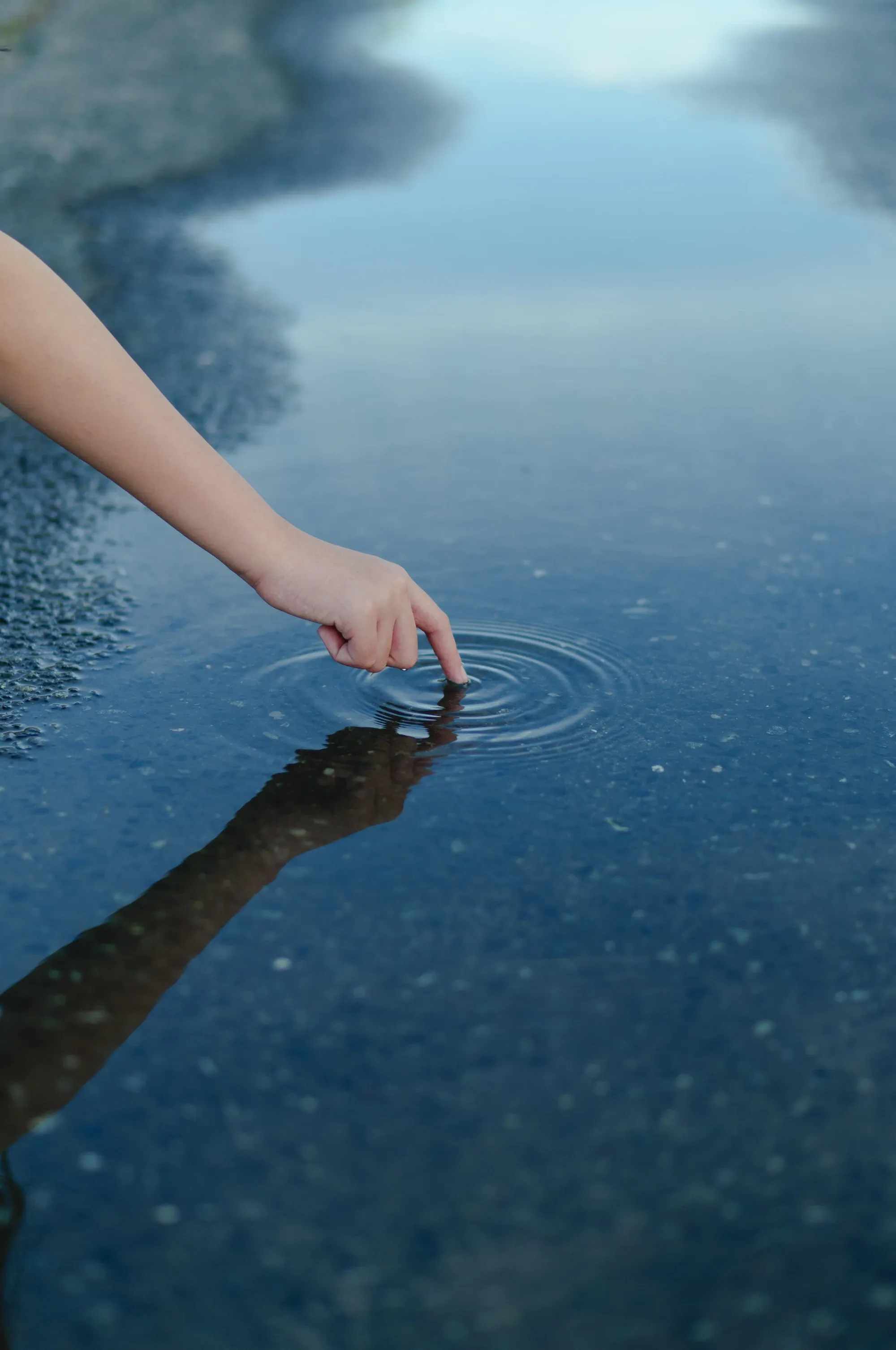 Рука касается воды и создаёт круги на поверхности